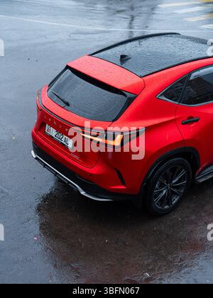 Bichkek, Kirghizistan - 12 octobre 2024 : vue arrière à angle élevé d'un VUS Lexus NX350 rouge sur une rue asphaltée humide, montrant des gouttes de pluie sur la surface Banque D'Images