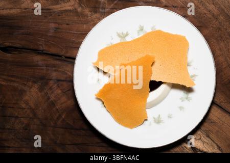 Deux gaufrettes croustillantes sont servies avec un dessert crémeux sur une assiette décorative, offrant une friandise sucrée sur une table en bois. Banque D'Images
