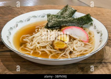 Un bol de ramen avec nouilles, bouillon, algues, œufs et kamaboko est servi, offrant un repas réconfortant et savoureux. Banque D'Images