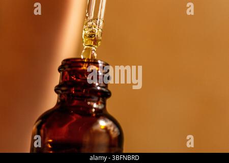 Gros plan de la main féminine laissant soigneusement tomber l'huile corporelle aromatique avec une pipette en verre. Soins spa concept d'aromathérapie auto-soin. Banque D'Images
