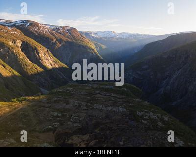 Vue imprenable par drone sur une majestueuse vallée ensoleillée et les montagnes en Norvège à l'aube, un paysage naturel avec des sommets enneigés. Banque D'Images