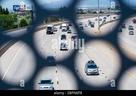 Orem, Utah – 2 juin 2025 : la circulation en direction du nord se déplace le long de l'Interstate 15 comme vu à travers une ouverture structurelle dans le pont piétonnier UVU à Orem, UT. Banque D'Images