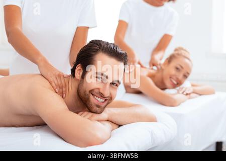 Couple joyeux recevant un massage du cou au spa Banque D'Images