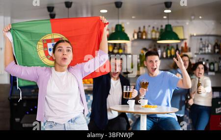 Les fans du drapeau du Portugal célèbrent la victoire de leur équipe préférée au bar à bière Banque D'Images