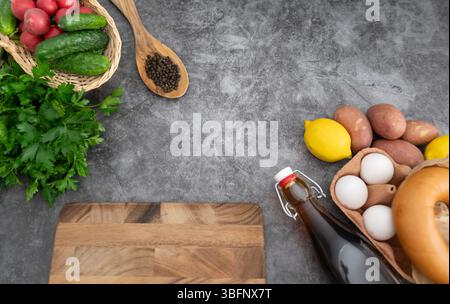 Composants traditionnels okroshka affichés sur une surface en bois sombre avec une planche à découper centrale en bois Banque D'Images