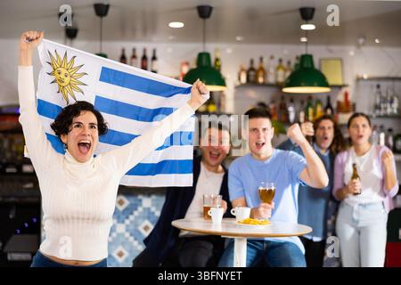 Les fans du drapeau de l'Uruguay célèbrent la victoire de leur équipe préférée au bar à bière Banque D'Images