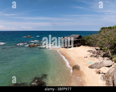 Petite cabane en bord de mer sur une plage de sable entourée d'eau turquoise et de côtes rocheuses. Koh Tao, Thaïlande. Banque D'Images