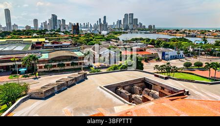 Vue sur les gratte-ciel modernes et les quartiers riverains de Carthagène, Colombie vue depuis la plate-forme surélevée de Castillo San Felipe de Barajas. La photo contraste les structures coloniales en pierre au premier plan avec l'architecture urbaine contemporaine au loin sous la lumière vive de l'après-midi Banque D'Images