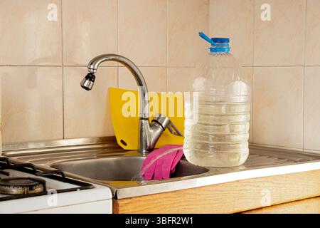 Une bouteille avec un trou comme robinet à main dans la cuisine comme alternative à l'eau courante, un robinet temporaire fait maison pendant une panne d'eau Banque D'Images