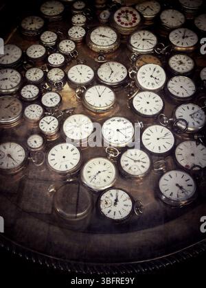 Une variété de montres de poche vintage sont disposées soigneusement sur une surface réfléchissante dans un magasin d'antiquités Banque D'Images