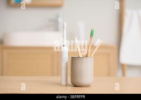 Support de brosses avec brosse à dents électrique sur table dans la salle de bain Banque D'Images
