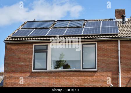 Pays-Bas : ancienne maison en rangée avec panneaux solaires et caloducs solaires installés côte à côte sur un toit en tuiles de béton gris dans le village néerlandais d'Ooste Banque D'Images