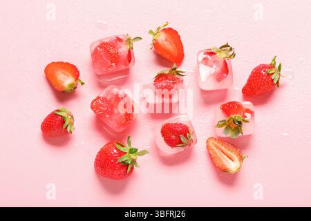 Fraises congelées dans des glaçons sur fond rose Banque D'Images