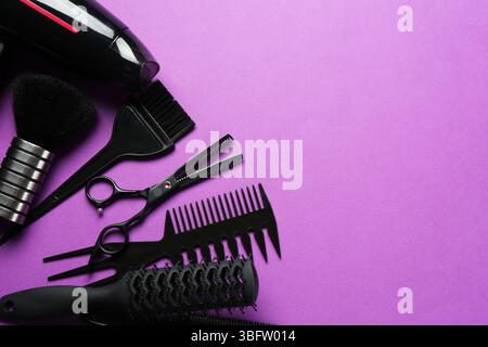 Différents outils de coiffeur sur fond violet, plat. Espace pour le texte Banque D'Images