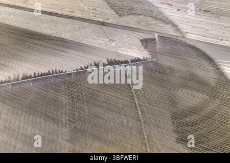 Vue aérienne du système d'irrigation arrosant le champ de ferme pendant la saison sèche. Arroseur industriel pulvérisant de l'eau sur le sol des terres agricoles pour la croissance des cultures pendant Banque D'Images