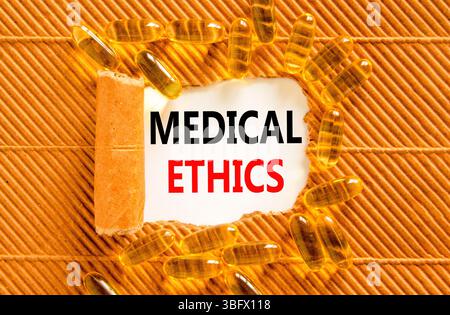 Symbole d'éthique médicale. Mots conceptuels éthique médicale sur un beau livre blanc. Comprimés de pilules jaunes. Beau fond marron. Vie médicale saine Banque D'Images