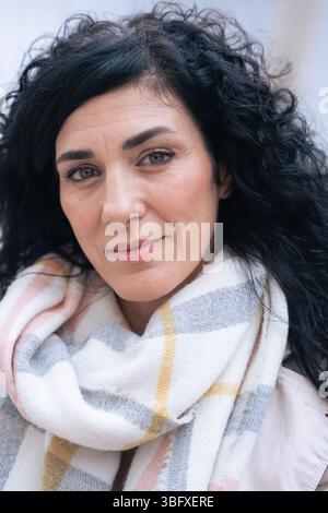 Portrait individuel femme confiante avec cheveux noirs bouclés et foulard souriant Banque D'Images
