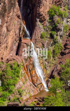 Cascade pittoresque descendant des formations rocheuses rouges dans les Alpes françaises, région Provence Alpes Côte d'Azur Banque D'Images