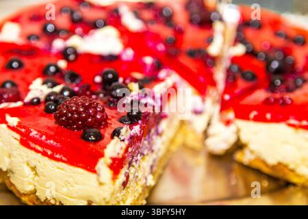 Tranche de gâteau au fromage avec des baies de cassis sur une table dans une assiette blanche. Banque D'Images
