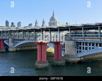 LONDRES, ANGLETERRE – 6 AVRIL 2025 : vue du pont ferroviaire Blackfriars et de la gare sur la Tamise avec la cathédrale Saint-Paul en arrière-plan. Banque D'Images