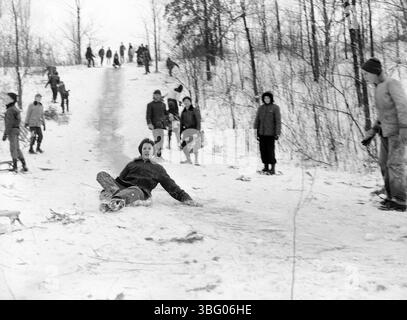 Photographie prise par A.V. Shirk vers 1955 montrant des gens en traîneau à Devil's Hill dans l'Ohio. A.V. Shirk, un photographe né en 1938, a capturé divers événements dans l'Ohio et au-delà, y compris des concerts de musique folk et des scènes locales. Shirk a travaillé chez WOSU et a produit des émissions de radio avant de passer à la photographie commerciale. Cette image fait partie de sa vaste collection documentant la vie dans l'Ohio du milieu du XXe siècle. Banque D'Images