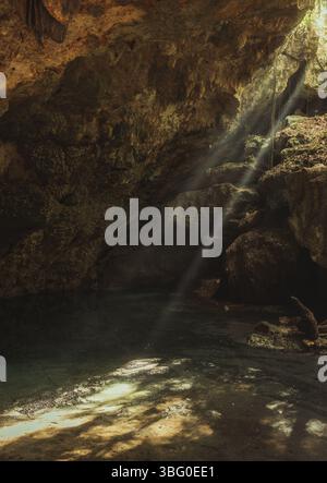 Caverne calcaire avec de l'eau douce dans la péninsule du Yucatan avec les rayons du soleil entrant et la végétation tropicale à l'extérieur par une journée ensoleillée au Mexique Banque D'Images