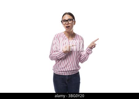 Jeune femme de bureau joyeuse habillée d'une chemise rose-blanche pointe vers un espace vide Banque D'Images