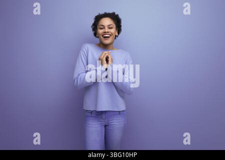 Jolie jeune femme latine avec des cheveux afro dans des vêtements de printemps élégants flirtant Banque D'Images