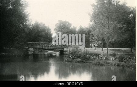 Cette photographie de 1897 montre un lac et un pont rustique dans le parc municipal (plus tard Schiller Park), mettant en évidence le développement historique et la beauté naturelle du parc. Banque D'Images