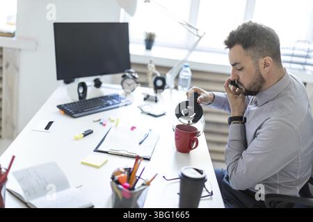 Un homme barbu dans une chemise claire et un pantalon sombre travaille au bureau. photo avec profondeur de champ Banque D'Images