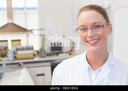 Technicienne de laboratoire portant une blouse blanche analysant l'échantillon sur paillasse avec hotte d'aspiration, espace de copie Banque D'Images