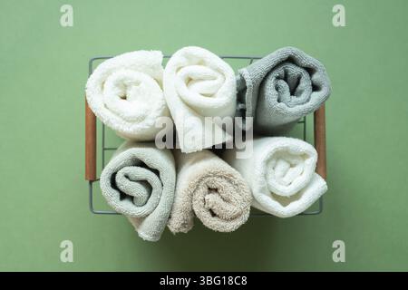 Serviettes de douche dans la salle de bains dans un panier sur fond vert. vue de dessus Banque D'Images