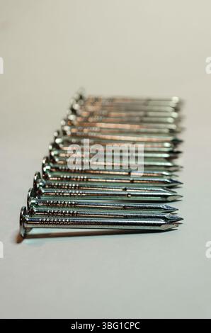rangée de clous de toiture argentés avec les plus proches en focus sélectif sur un fond blanc Banque D'Images