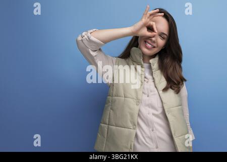 Jolie jeune femme brune caucasienne en gilet de couleur crème posant sur fond de studio Banque D'Images