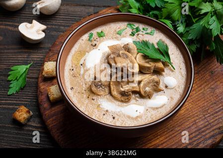 Soupe à la crème de champignons dans un bol garnie de croûtons, champignons frais et herbes près, texture crémeuse. Repas maison de saison d'automne - champignon mu Banque D'Images