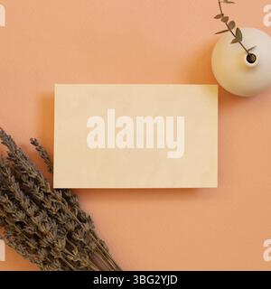 Bloc-notes vierge, papier vide avec fleurs sèches lavande et pot à fleurs d'eucalyptus sur fond de corail. pose à plat, vue de dessus, espace de copie Banque D'Images