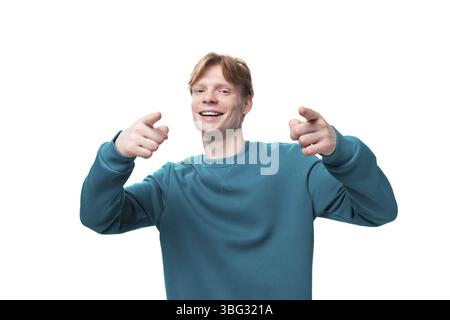 Jeune homme positif avec les cheveux roux montre ses mains sur l'espace pour les nouvelles Banque D'Images