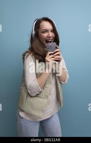 Jeune femme brune énergique se relaxant à la musique en utilisant des écouteurs et un téléphone portable Banque D'Images