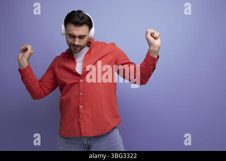 Un homme européen de 35 ans aux cheveux sombres aime écouter sa musique préférée à partir d'un casque Banque D'Images