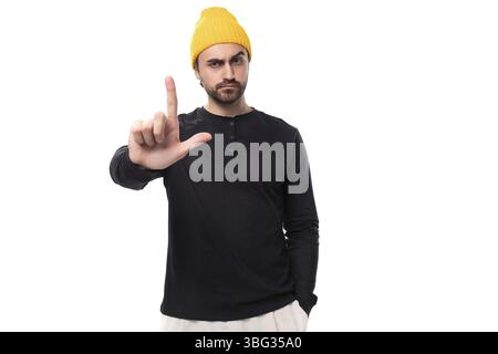 Jeune brune modèle masculin confiant avec une barbe vêtue d'une veste noire et d'un chapeau jaune Banque D'Images