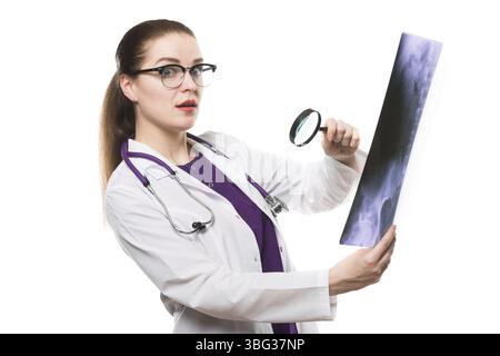 Belle joyeuse confus perplexe femme inexpérimentée médecin debout dans le bureau regardant les rayons X à travers la loupe faisant le diagnostic d'analyse avec l Banque D'Images