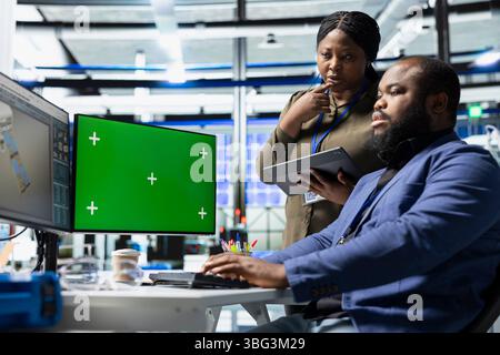 L'équipe d'ingénierie noire examine les panneaux solaires à côté de la clé chroma, montrant l'unité dans la technologie verte et l'énergie renouvelable respectueuse de l'environnement. Leadership opérationnel dans l'industrie manufacturière. Banque D'Images