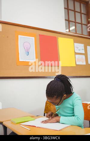Ordinateur portable est couché sur le bureau dans la salle de classe alors que le crayon repose sur le livre vert près de la fenêtre Banque D'Images