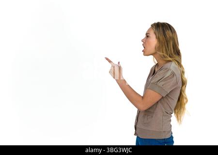 Femme adulte portant un chemisier beige et un Jean pointant le doigt et parlant dans un studio blanc, espace de copie Banque D'Images