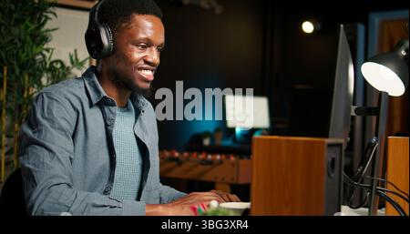 Black Guy éditeur vidéo travaillant avec deux moniteurs pour le contenu créatif, l'édition de séquences vidéo et l'étalonnage des couleurs pour la création de médias. Professionnel masculin travaille en post-production. Caméra A. Banque D'Images