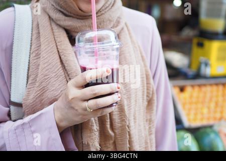 Femme appréciant le jus rafraîchissant dans le marché occupé Banque D'Images