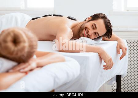 Couple profitant d'un massage de pierre couché et relaxant au salon de spa Banque D'Images