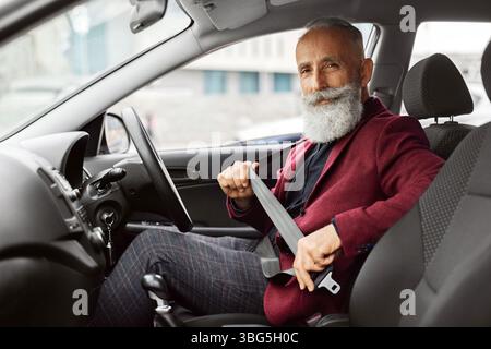 Un homme de famille fixe la ceinture de sécurité dans sa voiture Banque D'Images