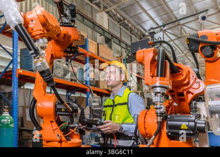 ingénieur professionnel, technicien robotique travaillent dans l'opérateur de contrôle de machine de bras de soudage de robot industriel moderne d'usine Banque D'Images
