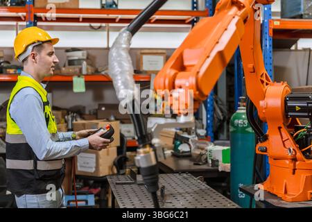ingénieur professionnel, technicien robotique travaillent dans l'opérateur de contrôle de machine de bras de soudage de robot industriel moderne d'usine Banque D'Images